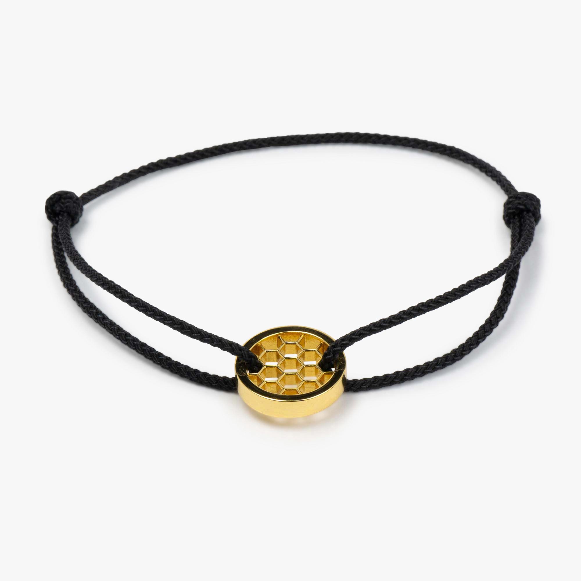 A black golf bracelet with a gold-plated circular charm featuring a hexagon pattern, displayed against a white background.