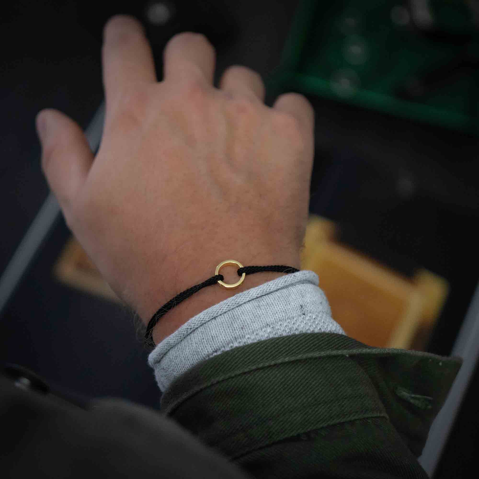 14k gold ring on black string bracelet