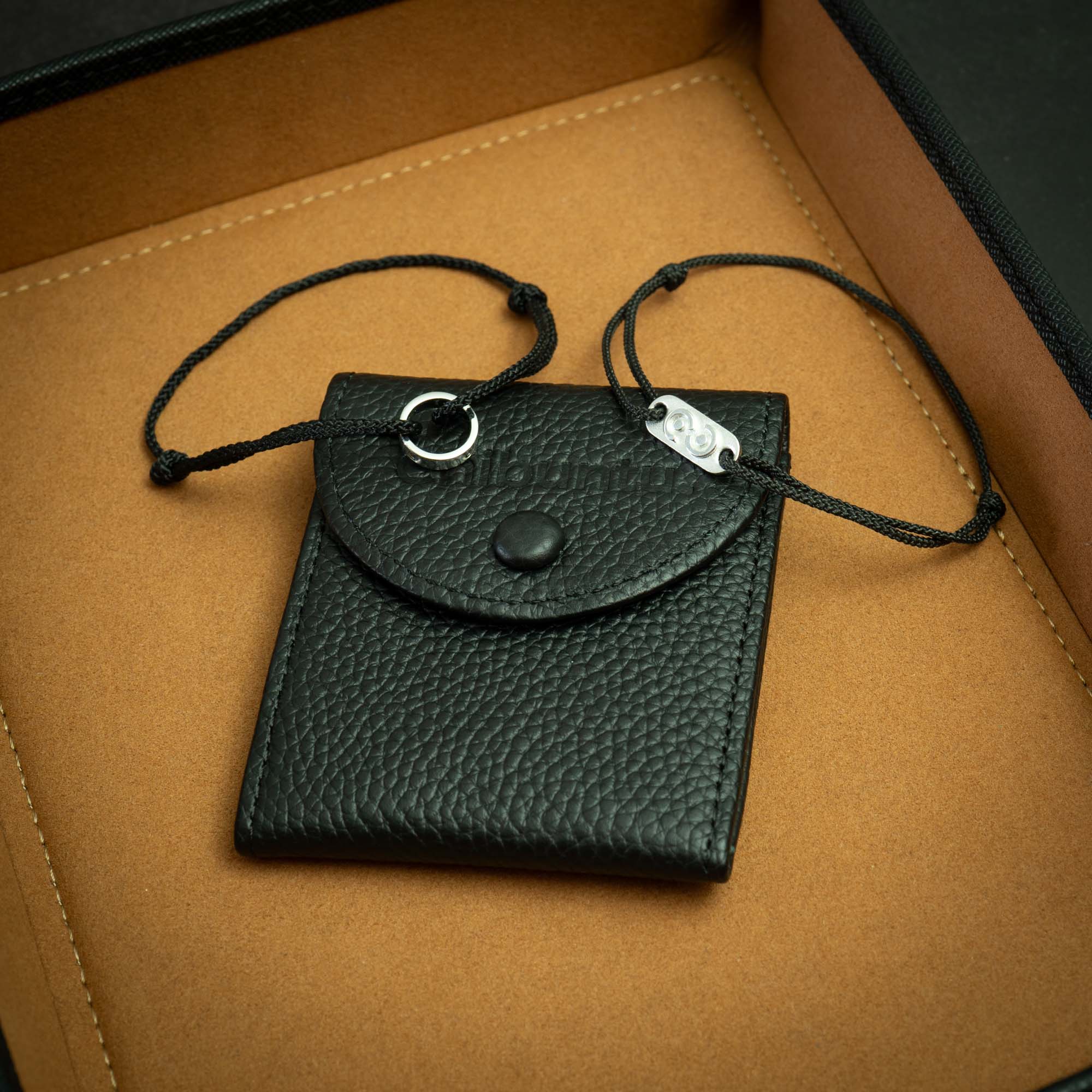 The image shows a black 925 silver jewelry set presented on a brown surface, including a bracelet and a tag, packaged in a black premium leather bracelet pouch.