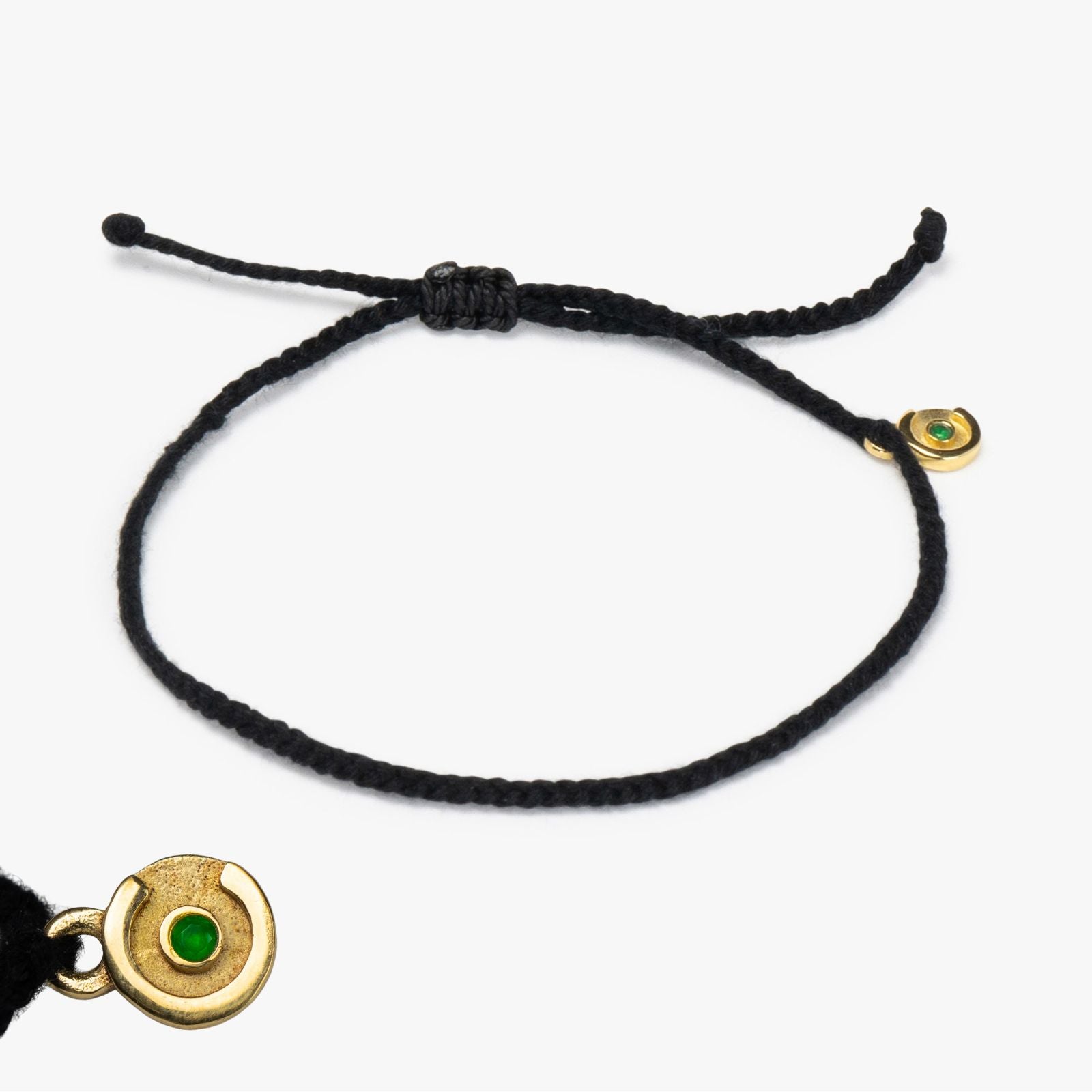 A black bracelet with a gold-plated charm featuring a green zircon stone, displayed against a white background.
