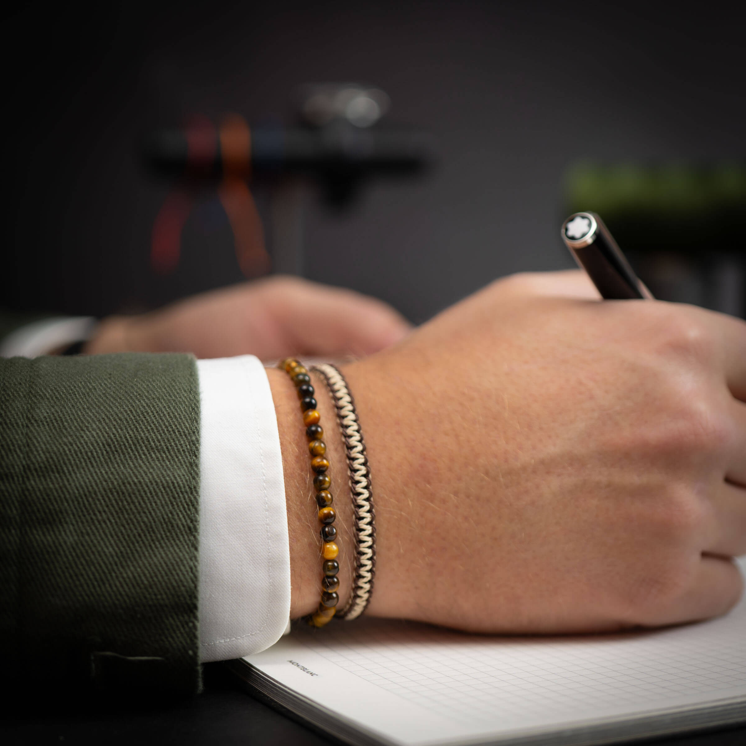 A person's wrist wearing a gold and black beaded bracelet with a charm.