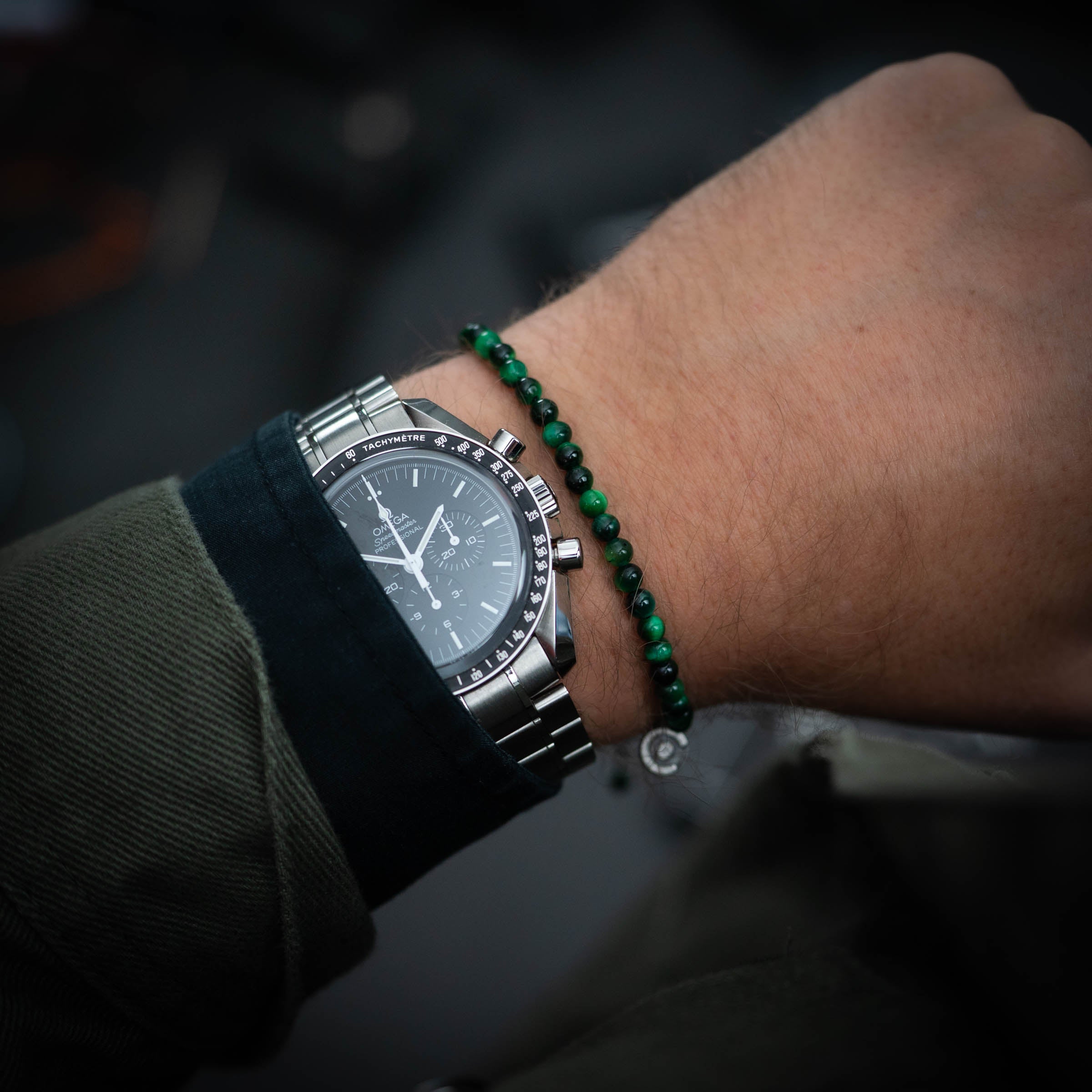 green tiger eye gemstone bracelet for men next to a Omega Speedmaster.