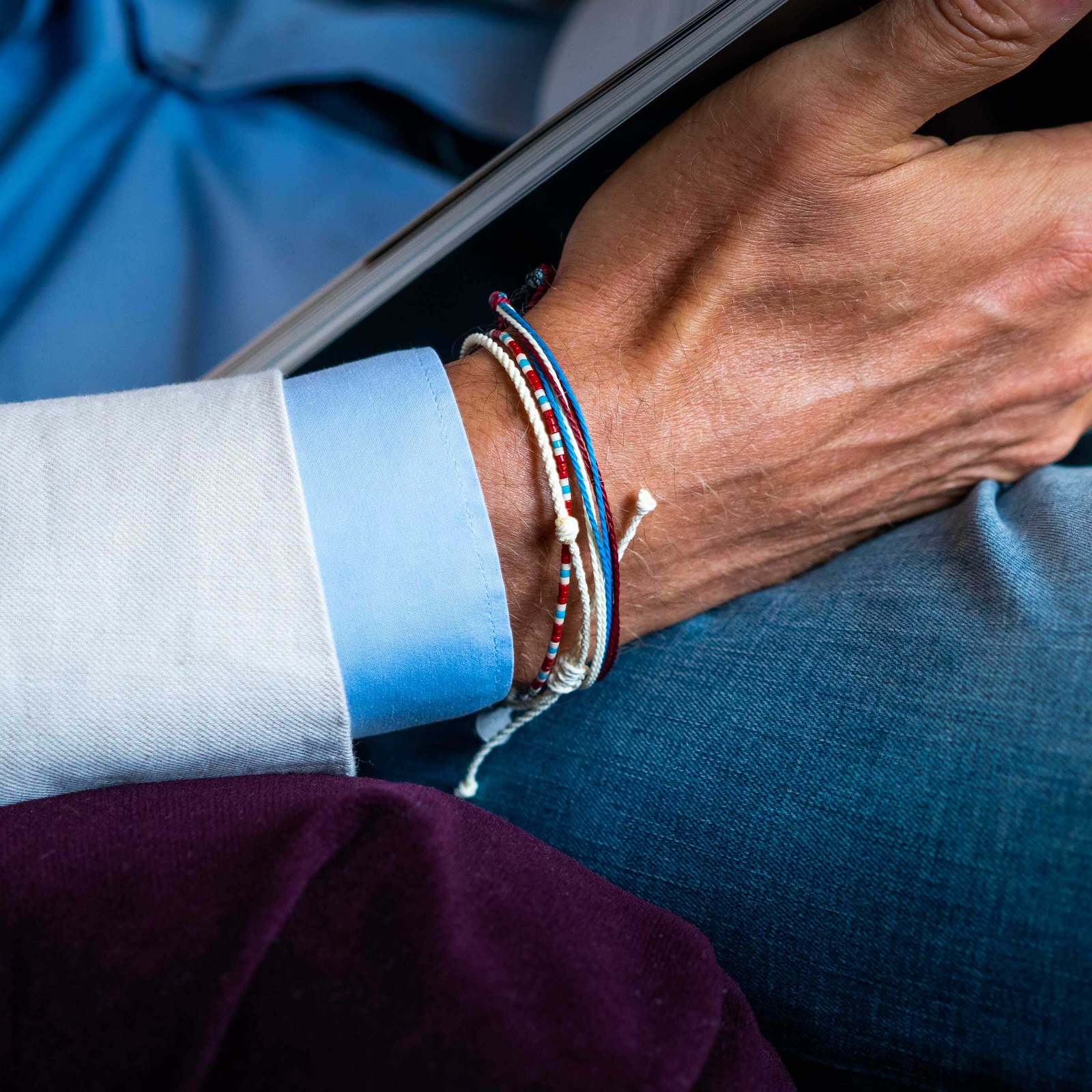 A close-up image of a wrist wearing three layered bracelets with a blue and white design.