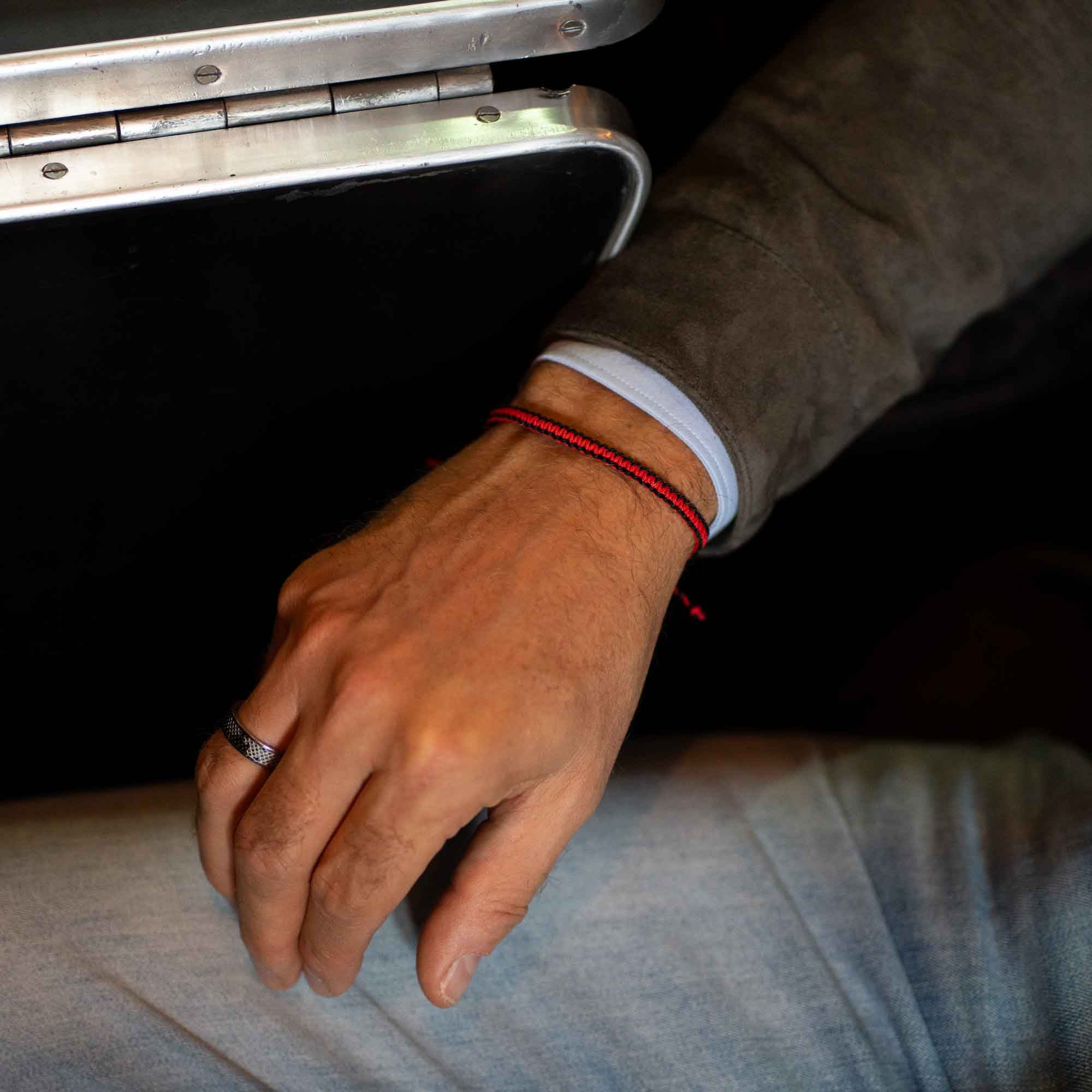 mens red and black bracelet on wrist in a train