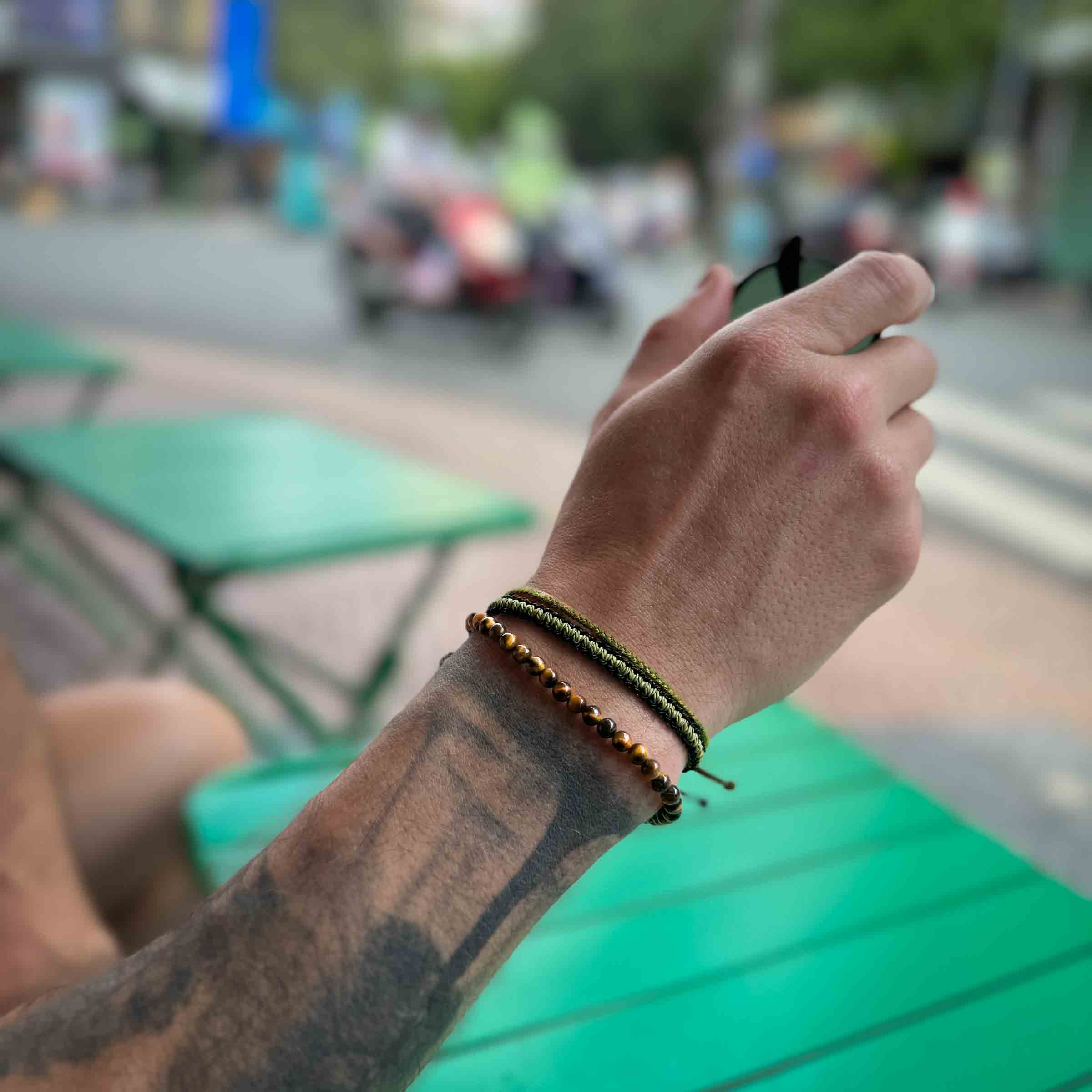 men's tiger's eye bracelet pack on male wrist holding sunglasses
