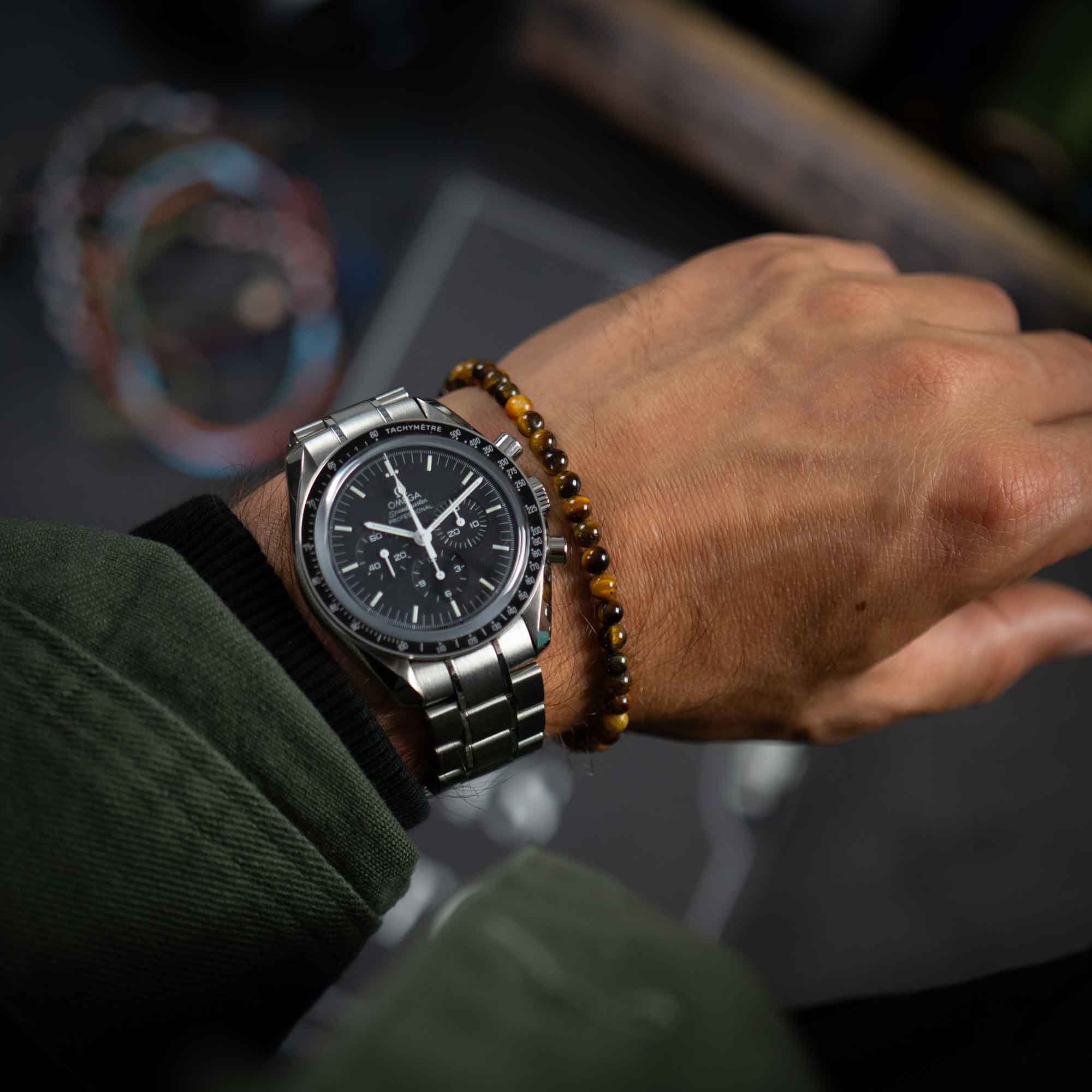 men's tiger eye gemstone bracelet next to an Omega Speedmaster Pro