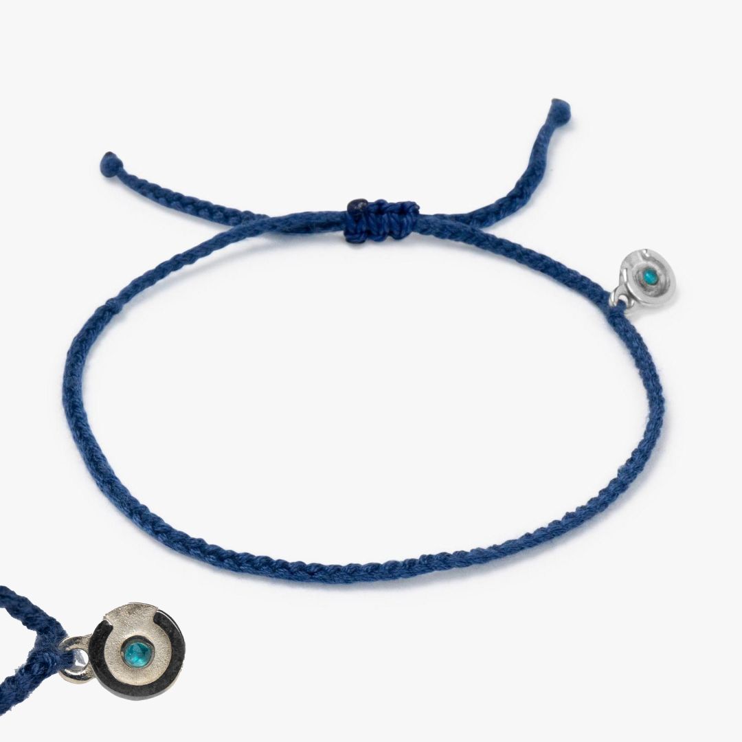 A navy blue bracelet with a 925 sterling silver charm and a blue topaz stone, displayed on a white background.