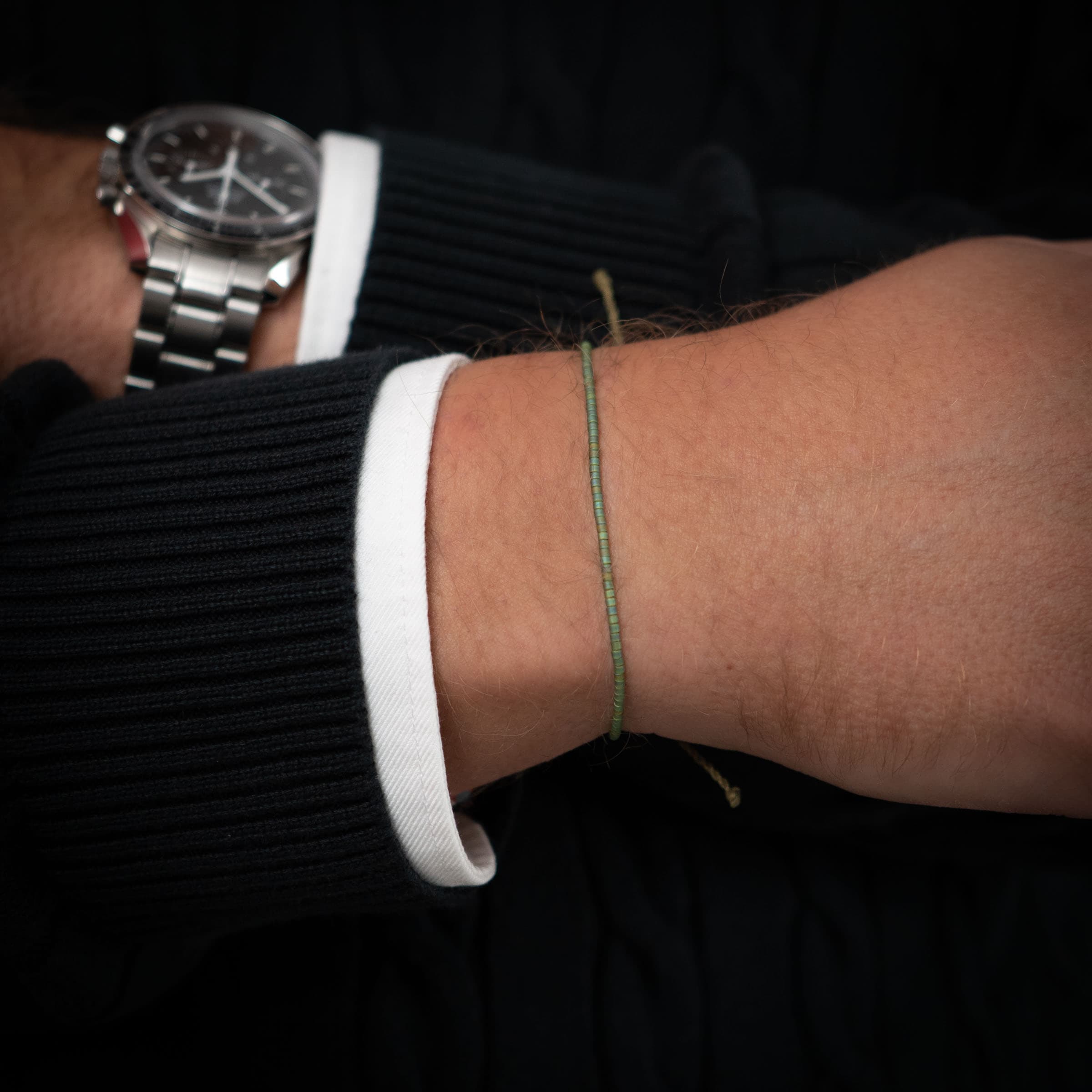 green men's beaded bracelet on wrist luxury watch from omega on the side