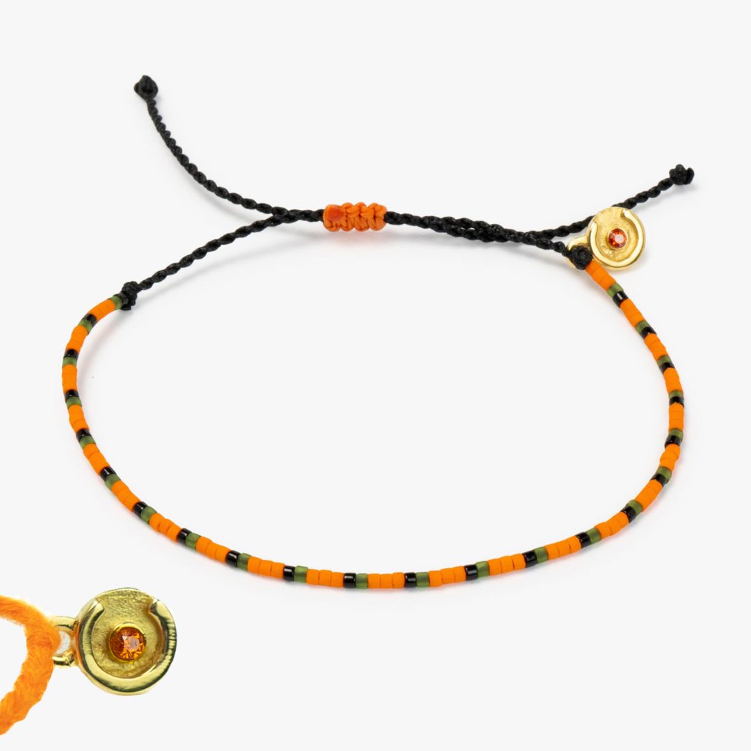 orange beaded bracelet with 14k gold charm on a white background.