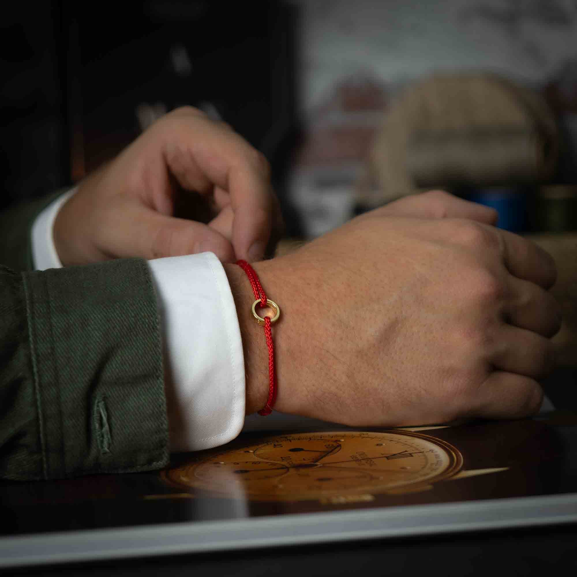 14k gold ring on red thread bracelet