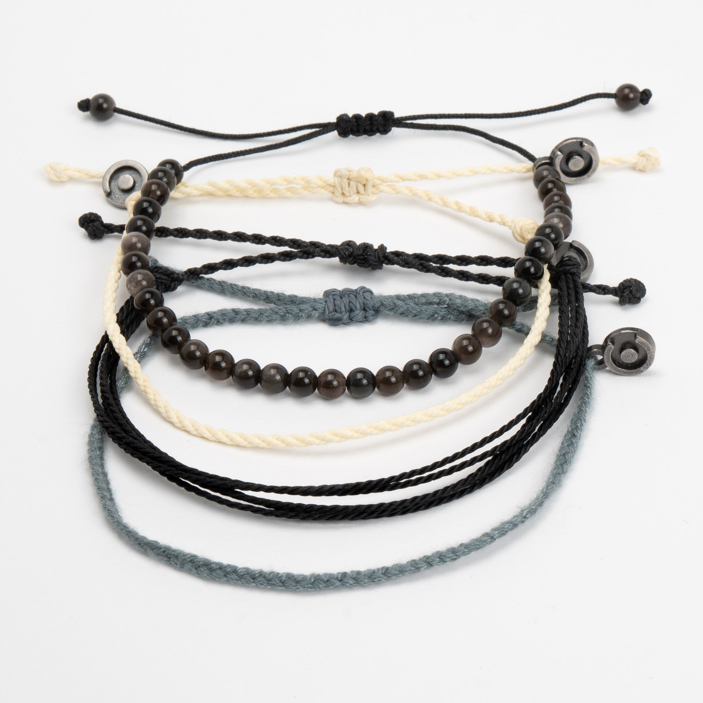A collection of four bracelets made with silver obsidian beads and wax-coated polyester, in black, blue, and beige colors.