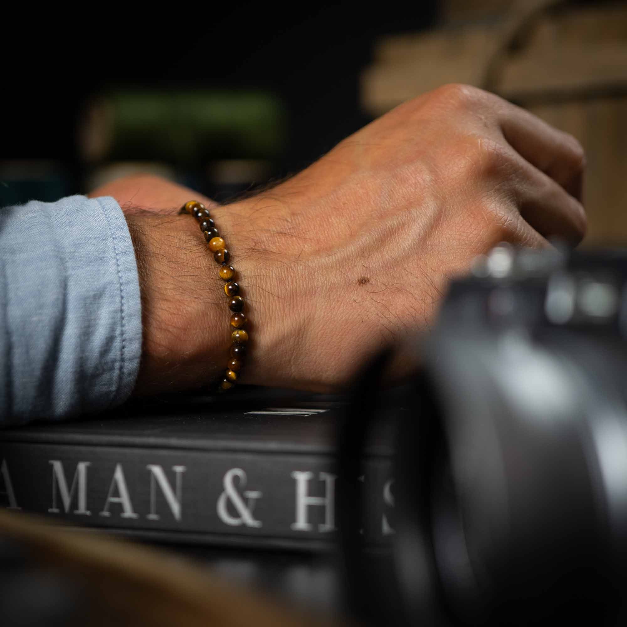 tiger eye bracelet pack next to the book a man and his watch
