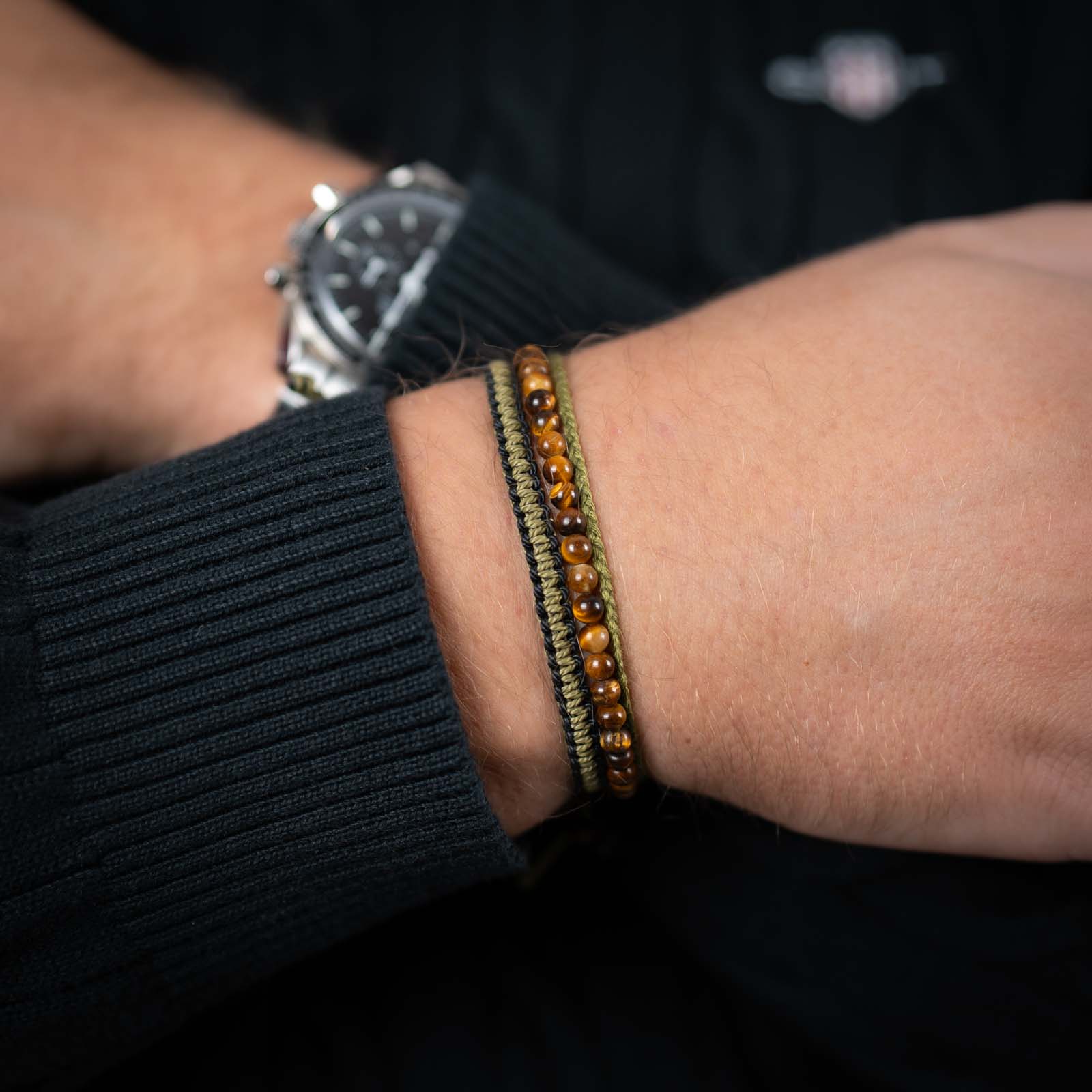 A person's wrist wearing a brown and black beaded bracelet with a metallic clasp