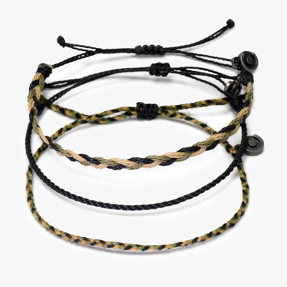 A set of three woven bracelets with gunmetal charms, two with a camouflage pattern and one solid color, likely black.