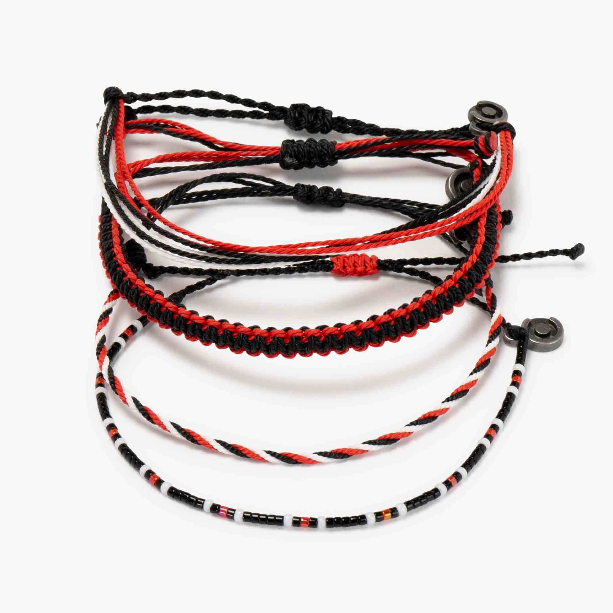 A collection of four woven bali bracelets in black, red, and white colors, with one featuring small multicolored beads.