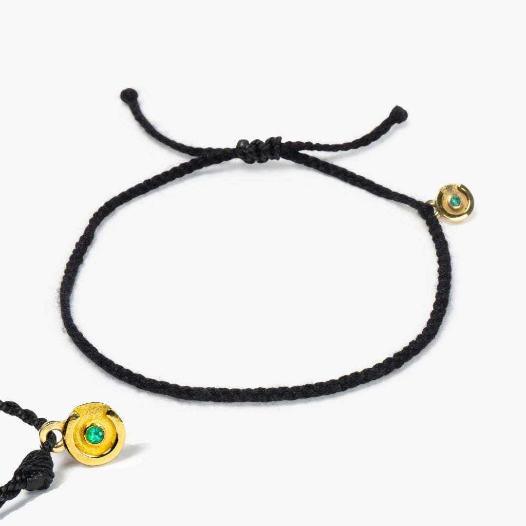 A black bracelet with a 14k gold plated power pose charm featuring a blue topaz stone, displayed on a white background.