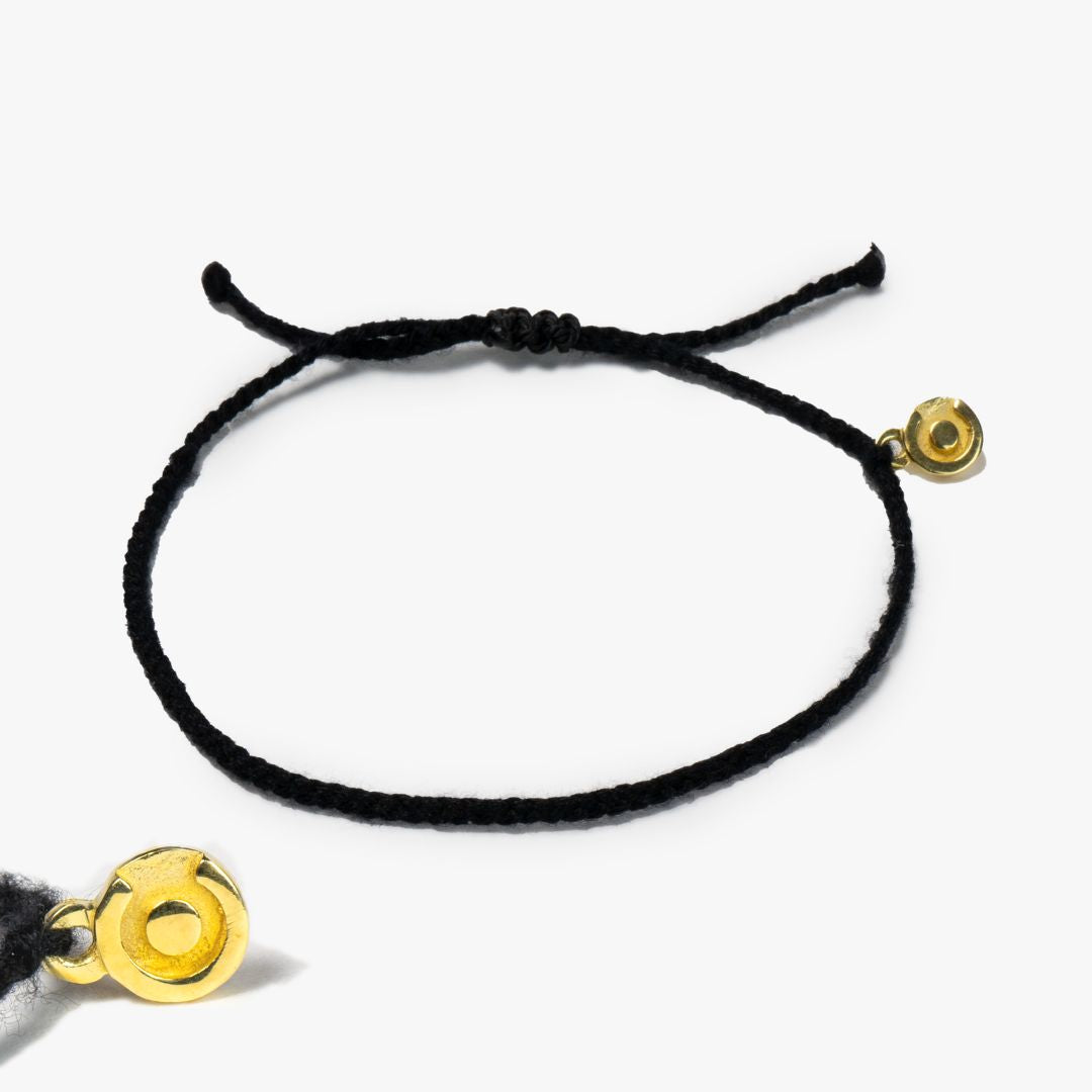 A black bracelet made of soft polyester with a 14k gold plated power pose charm, displayed against a white background.
