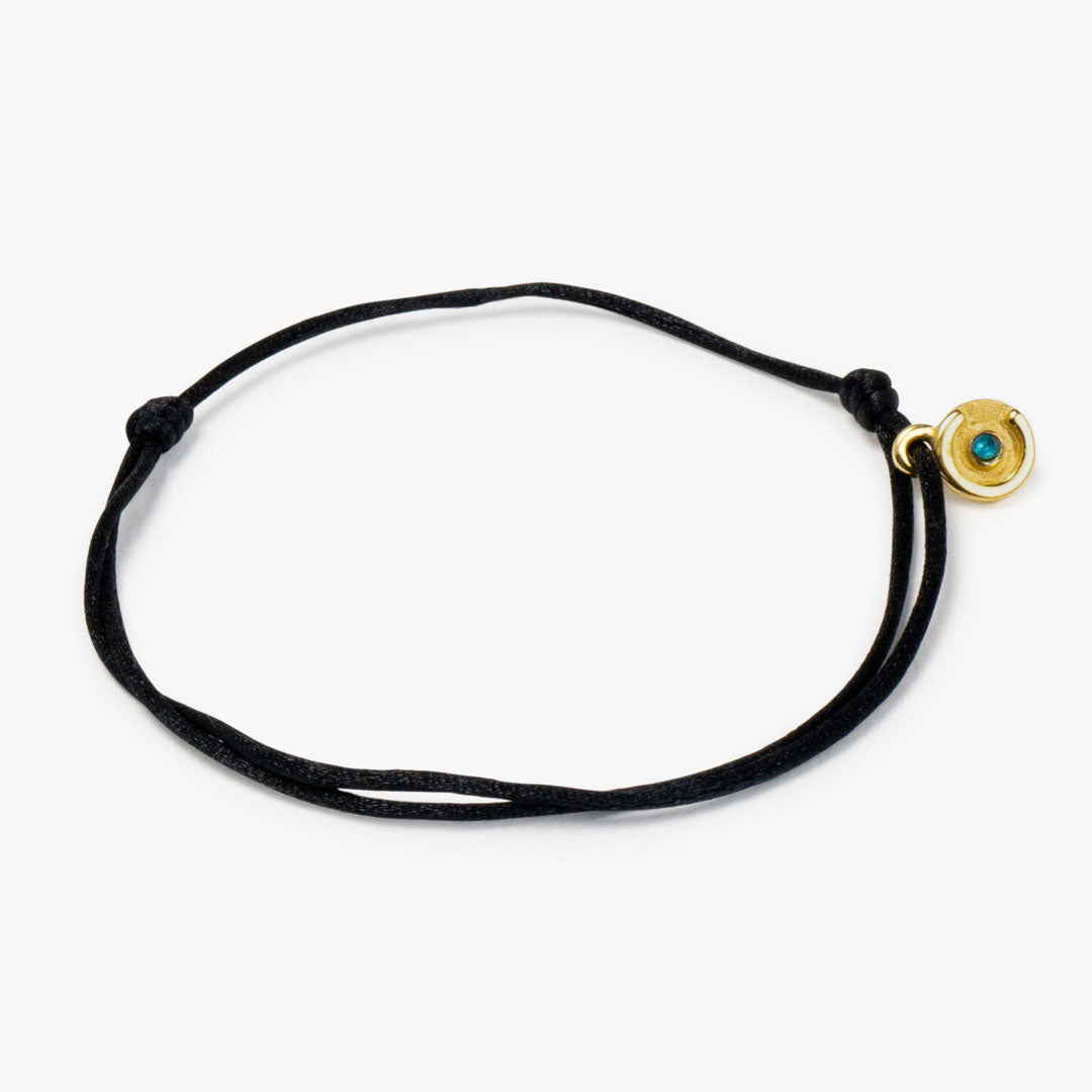 A black satin bracelet with a 14k gold plated power pose charm and a blue topaz stone, handmade from Amsterdam.