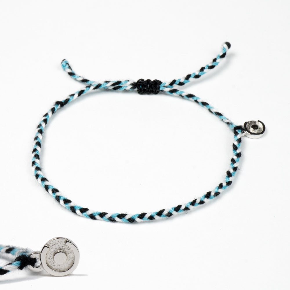 A two-tone (black and white) bracelet made of soft polyester with a 925 Sterling Silver power pose charm, displayed on a white background.