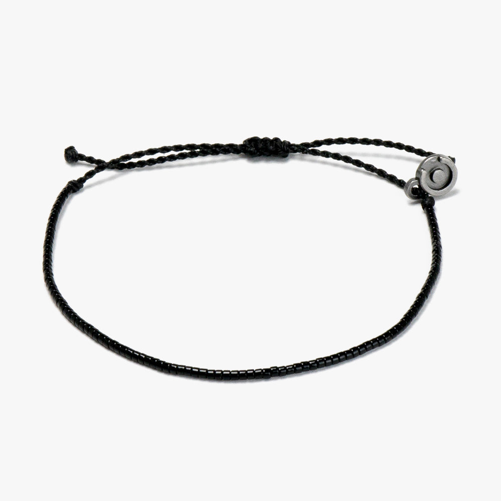 A black beaded bracelet with a gunmetal charm, displayed on a white background.