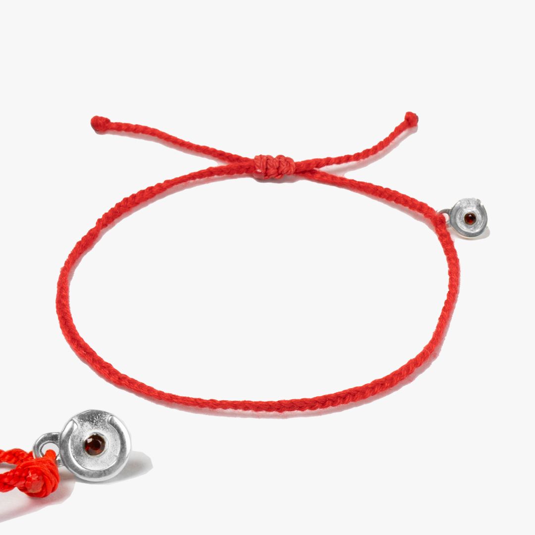 A red bracelet with a 925 silver charm featuring a red garnet stone, displayed against a white background.