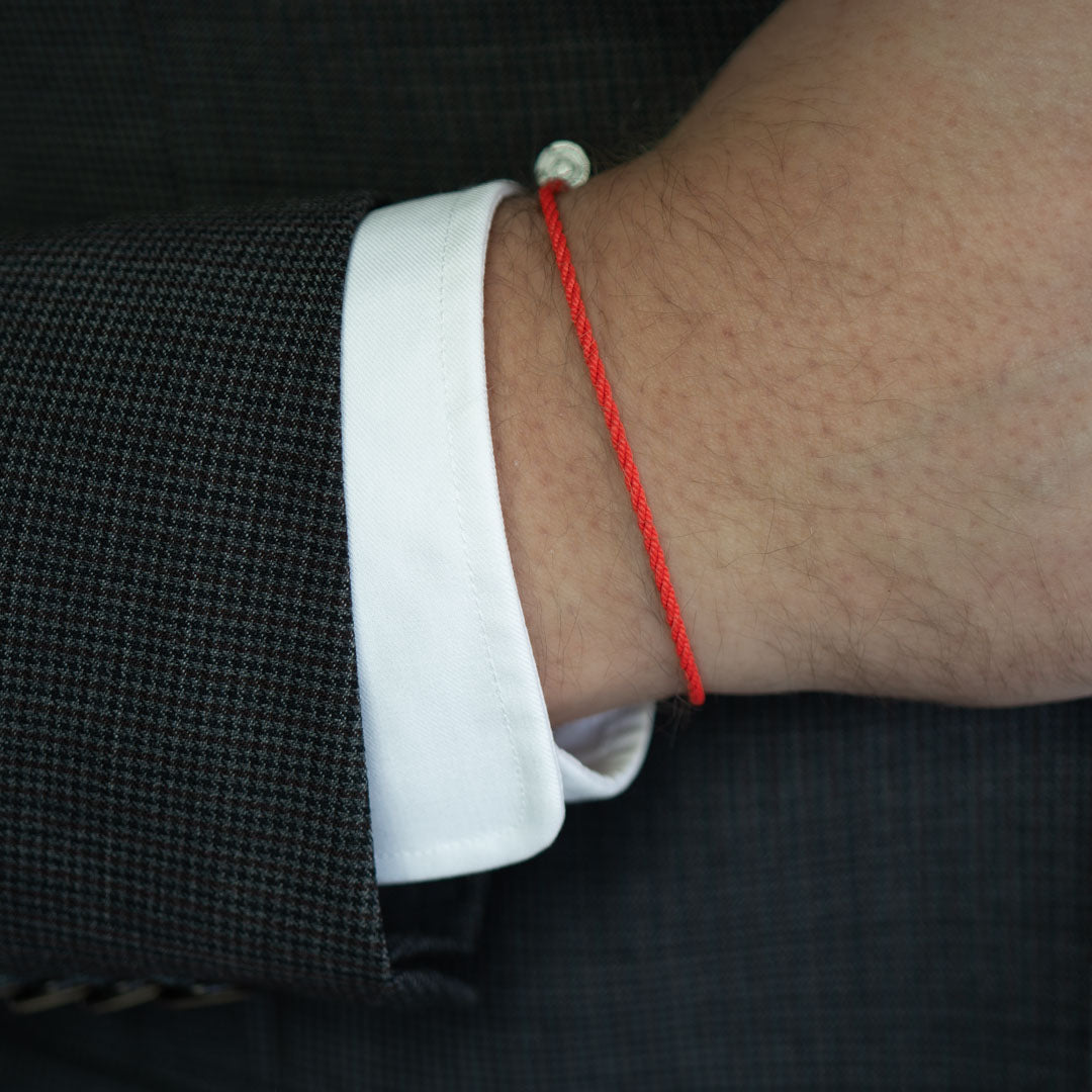 silver charm on red thread bracelet