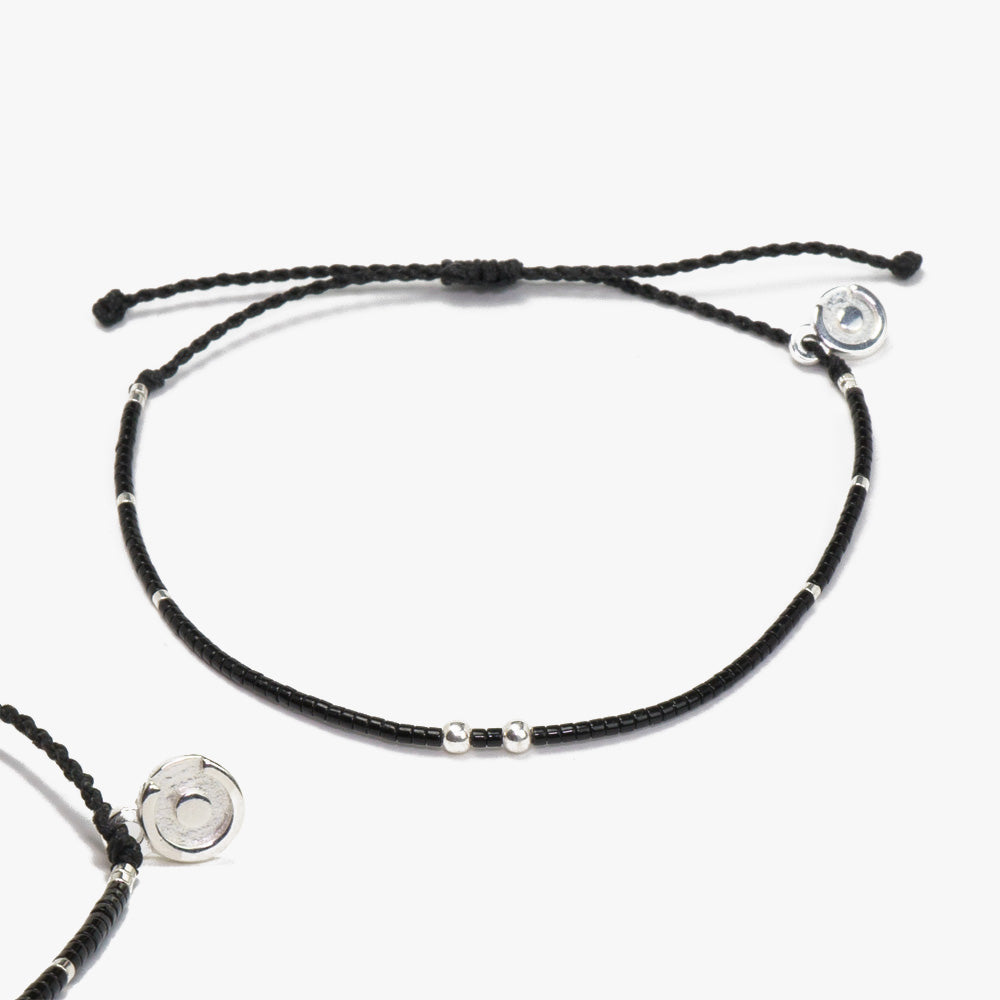 A black bracelet with silver accents and beads, featuring a 925 sterling silver charm, displayed on a white background.
