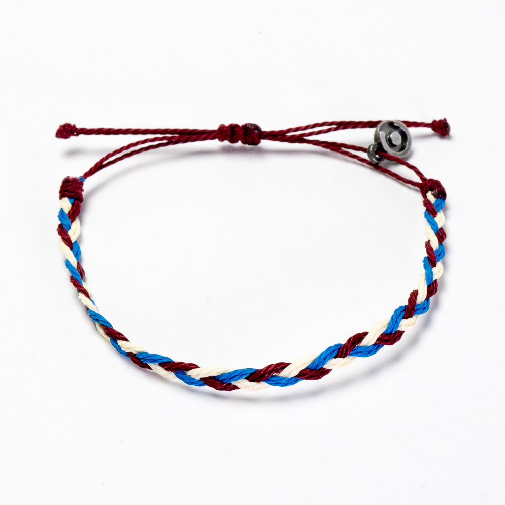 A woven bracelet with red, white, and blue strands, featuring a gunmetal power pose charm, on a white background.